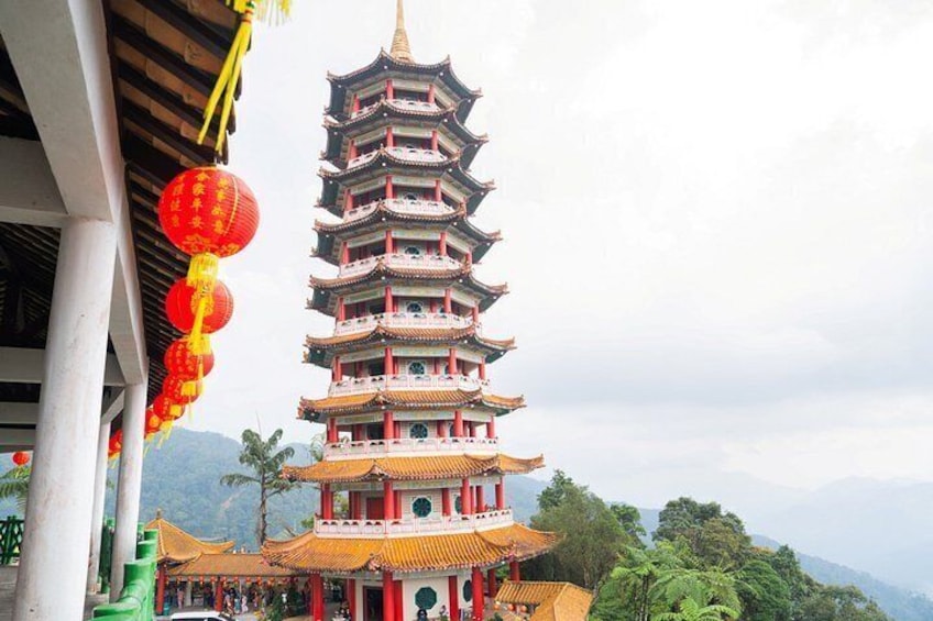 A multi-tiered pagoda with red lanterns, surrounded by lush greenery and mountains. 2