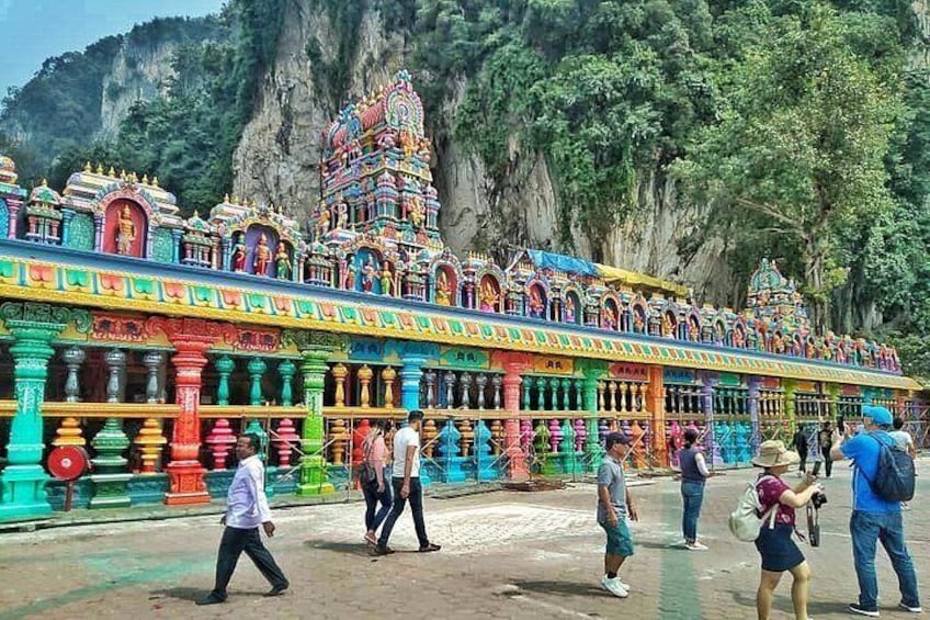 A colorful temple with intricate architecture, a paved walkway, and a mountainous backdrop. 4