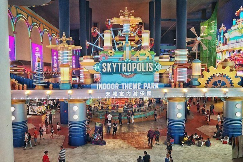 Un parque temático en interior con un gran cartel que dice 'SKYTOPOLIS INDOOR THEME PARK' y varias atracciones. 2