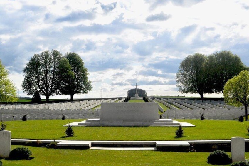 Ett minnesmärke med ett centralt monument, omgivet av en välskött gräsmatta och träd. 2