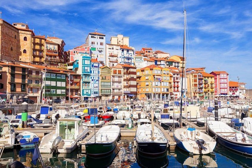 A marina with colorful buildings and numerous boats docked. 1