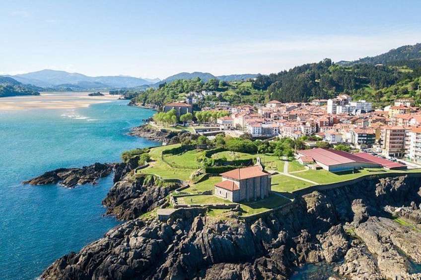 A coastal town with a church, buildings, and a rocky shoreline. 2