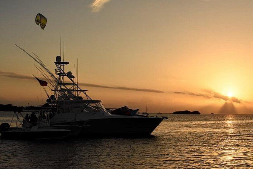 A large yacht at sunset with a parasail in the background. 1
