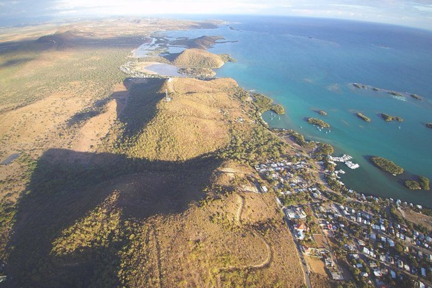 An aerial view of a coastal area with a small settlement, a large water body, and scattered islands. 2