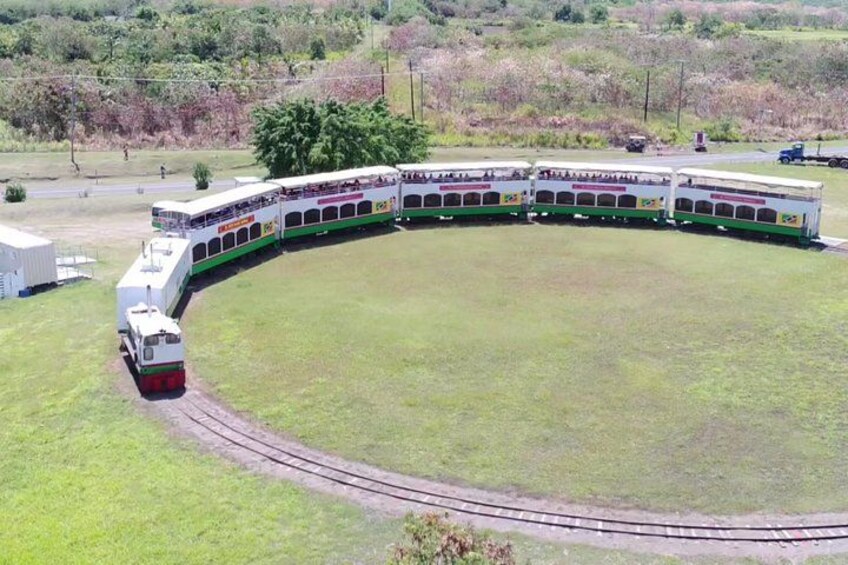 A train with multiple carriages curving around a grassy area. 4