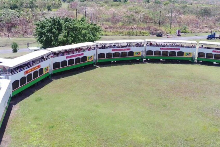 A series of connected buses parked in a semi-circle on a grassy field. 5