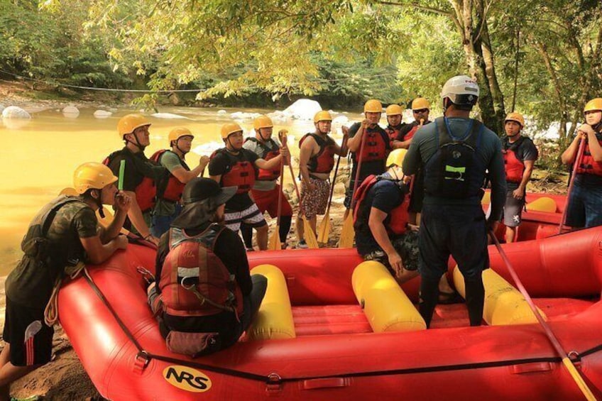 Eine Gruppe von Personen in einem roten Schlauchboot auf einem Fluss, mit Schwimmwesten und Helmen. 5