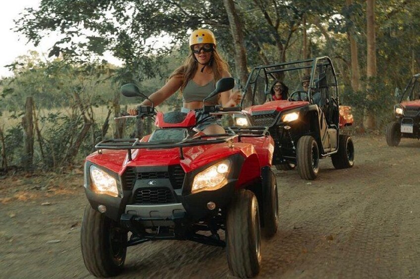 A person riding a red ATV on a dirt path in a wooded area. 4
