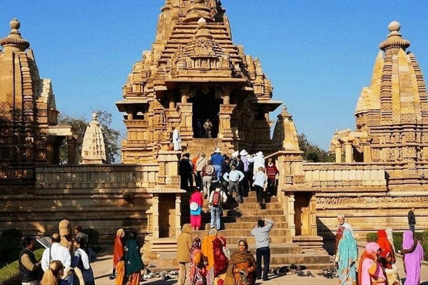 A temple with intricate carvings and a group of people ascending the steps. 3