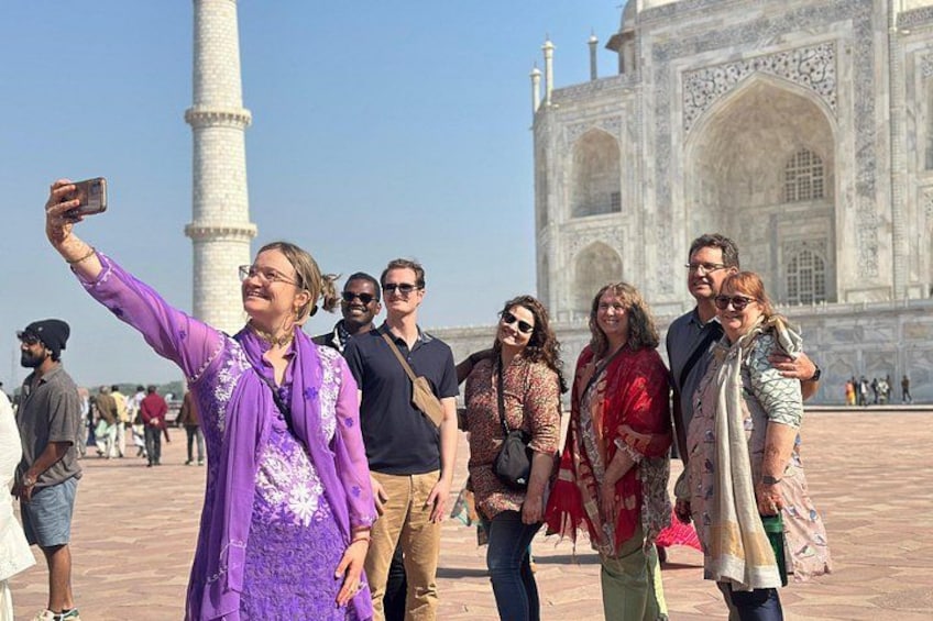 A group of people taking a selfie in front of the Taj Mahal. 1
