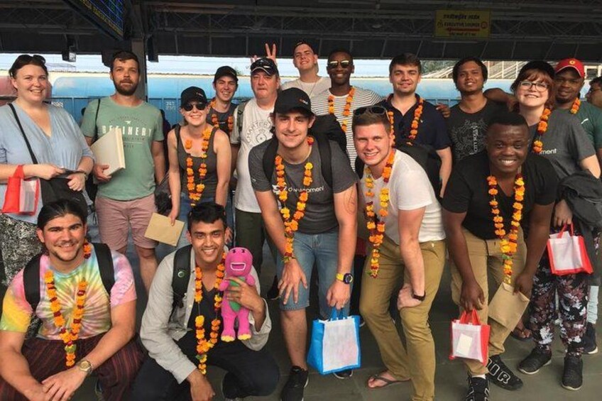 A group of people posing for a photo at a train station. 5
