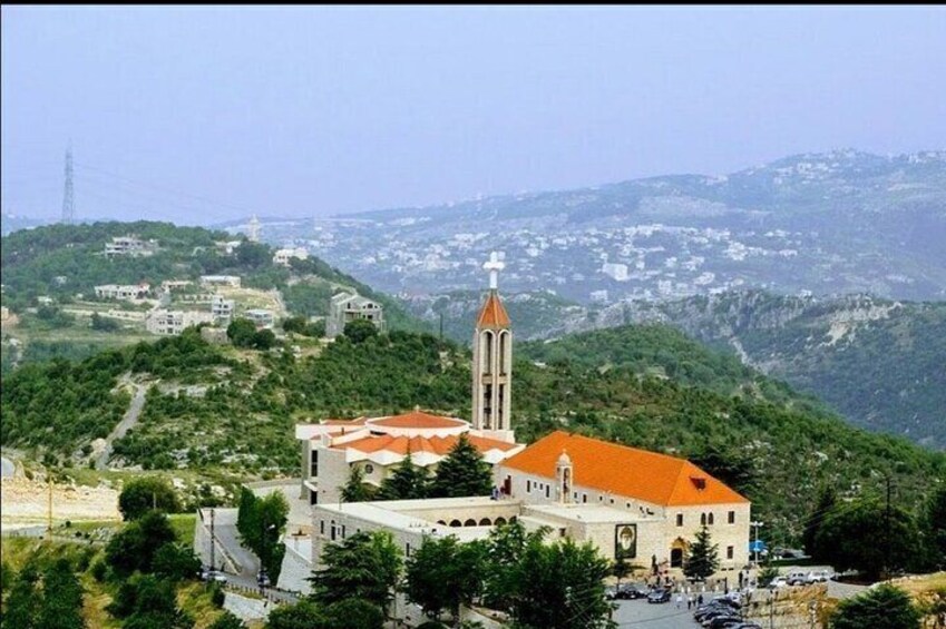 A church with a red roof and a bell tower on a hillside. 3