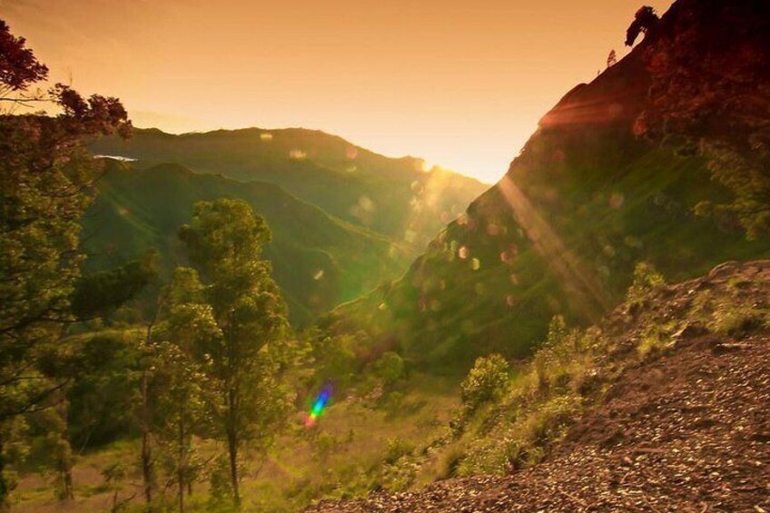 Un paysage montagneux avec un arc-en-ciel, des arbres et un premier plan rocheux. 5
