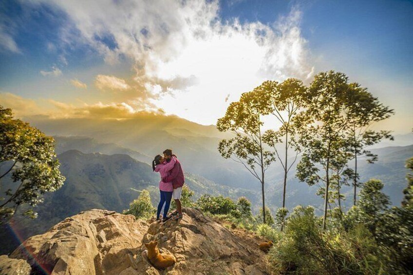 Une personne prend une photo au sommet d’une montagne, avec la vallée en contrebas en arrière-plan. 2