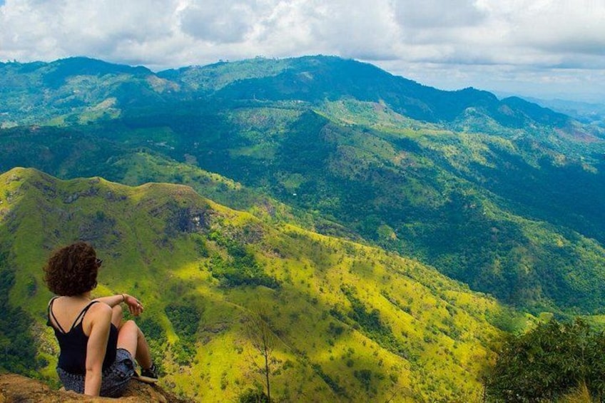 Une personne assise sur une colline, d’où elle a une vue panoramique sur un paysage montagneux. 3