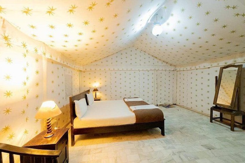 Een slaapkamer met een bed, nachtkastje, lamp en spiegel. 1