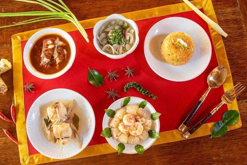 A variety of dishes on a red tablecloth, including a bowl of soup, a plate of noodles, and a dish with shrimp. 3