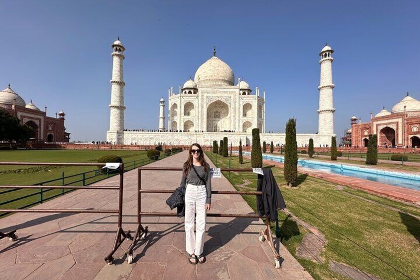 Eine Person steht vor dem Taj Mahal und hat einen klaren Blick auf das berühmte, weiße Marmor-Mausoleum sowie auf seine vier Minarette. 1