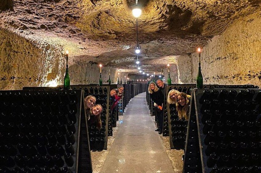 Una bodega con hileras de botellas de vino y algunas personas. 2