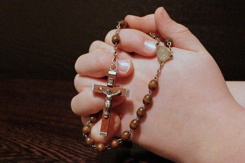 A hand holding a rosary with a crucifix pendant. 3