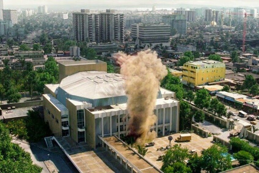 A building with a large plume of smoke or dust rising from its roof. 3