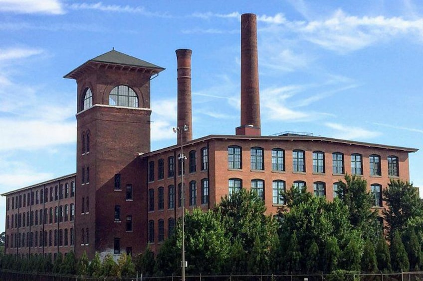 A large brick industrial building with two tall chimneys and a clock tower. 5