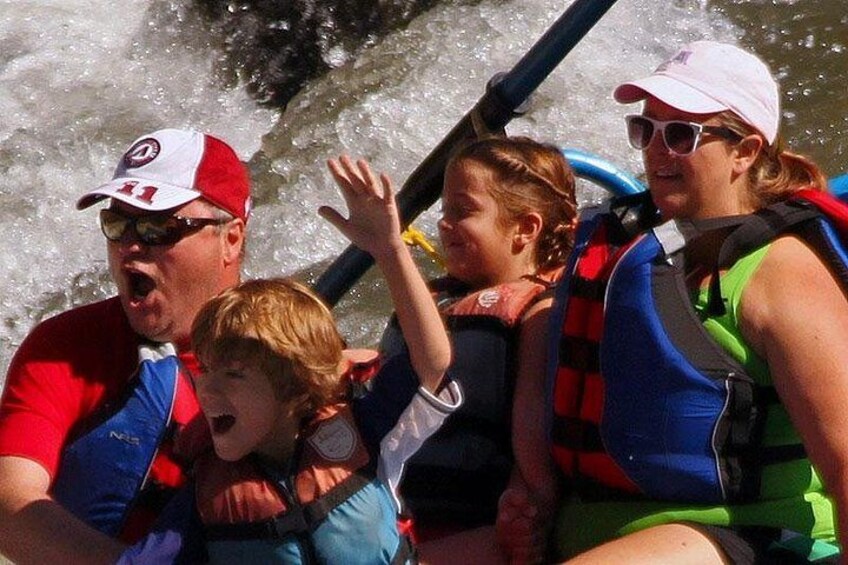 A group of people on a raft with water splashing around them. 3