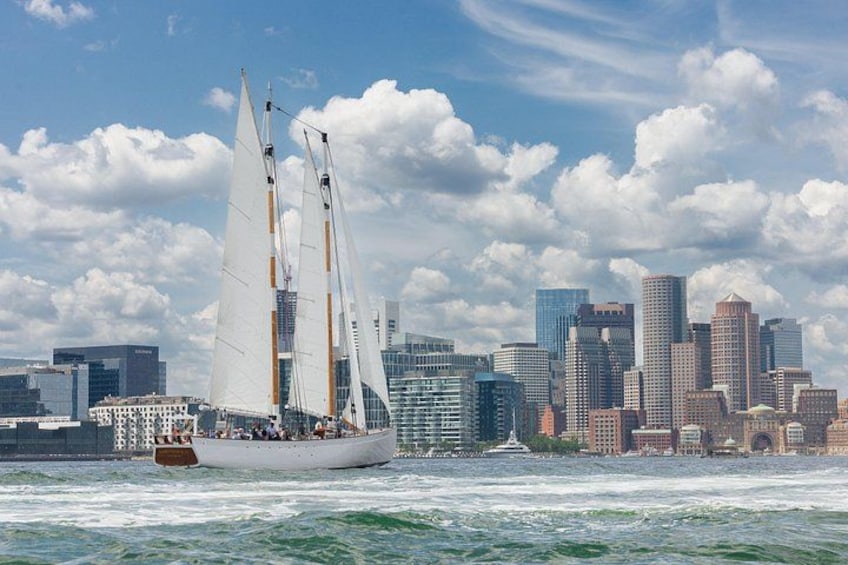 Een zeilboot op het water, met een stadsachtergrond op de achtergrond. 1