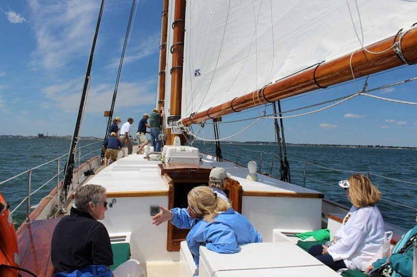 Een zeilboot met mensen op het dek, een heldere lucht en rustig water. 5