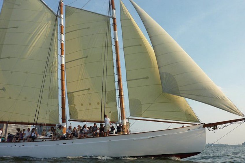Een zeilboot met meerdere zeilen, passagiers en een heldere lucht. 4