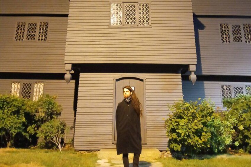 A person standing in front of a house with a dark door and windows with lattice designs. 3