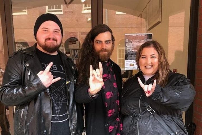 Three people in front of a building with a signboard. 5