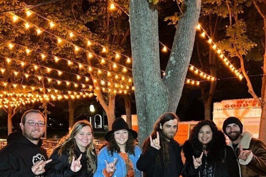 A group of people posing under a tree with string lights. 4