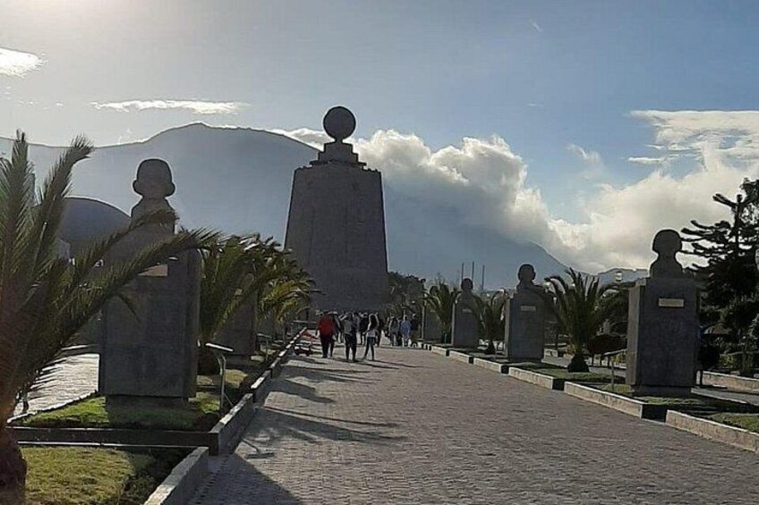 Un sentier pavé, bordé de statues et de palmiers, qui mène vers une montagne en arrière-plan. 3