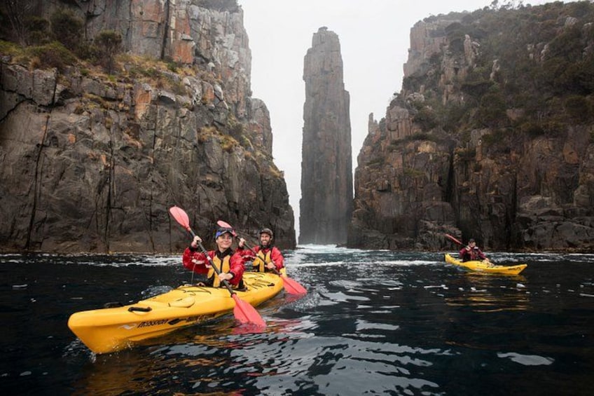 Kayakers in yellow kayaks navigating a narrow canyon with steep rock walls. 5