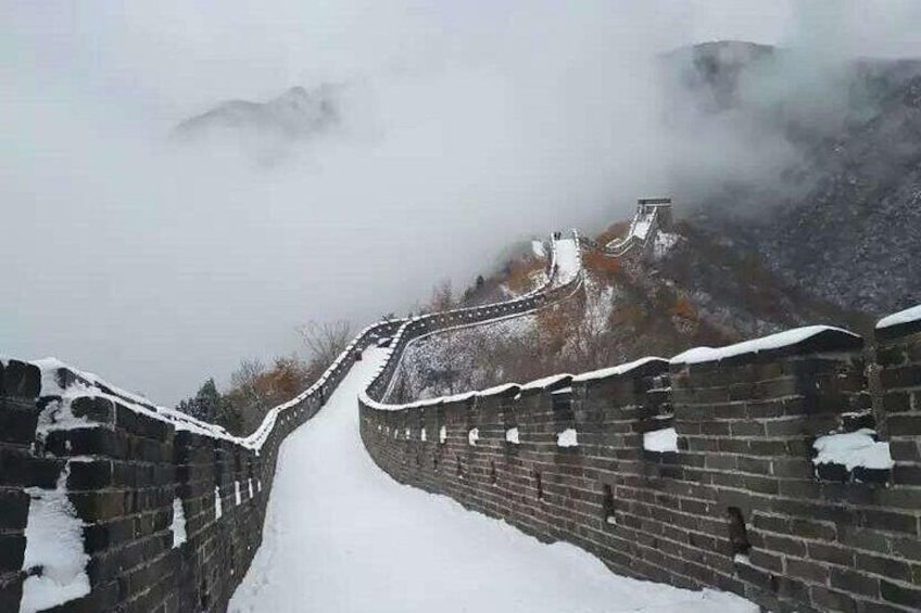 A snow-covered section of the Great Wall of China with a mountainous backdrop. 1