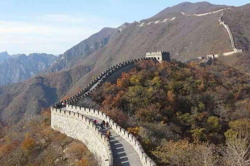 A winding stone wall with watchtowers, surrounded by autumn-colored trees and mountains. 5