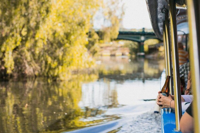 A person holding a bottle on a boat with a bridge in the background. 5