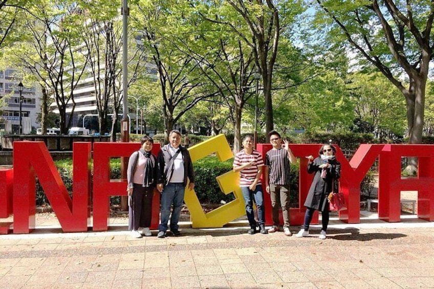 Un grupo de personas posando frente a letras rojas grandes que dicen 'NICE'. 1
