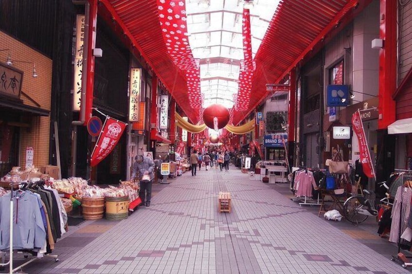 Una animada calle comercial con puestos, adornos rojos y letreros. 3