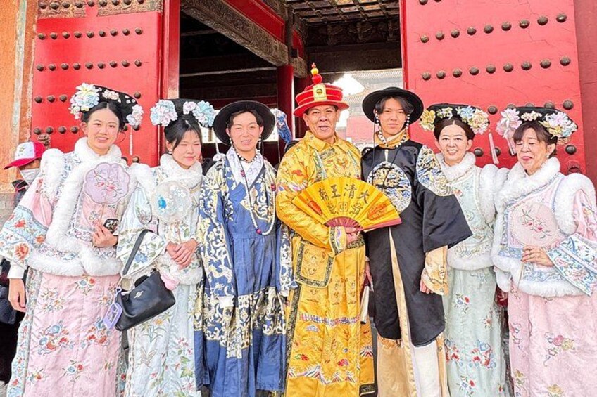 A group of people in traditional Chinese attire standing in front of a red gate. 4