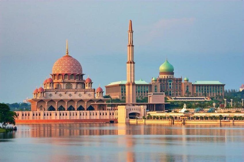 A mosque with a large dome and minaret, a tall tower, and a reflection in the water. 2