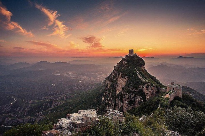 A mountainous landscape with a prominent peak, a watchtower, and a stone wall. 1