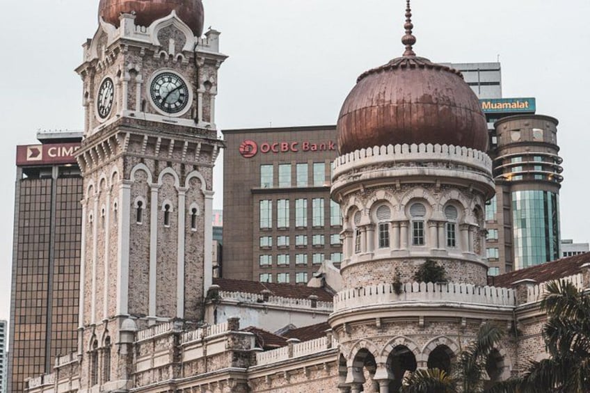 Un edificio histórico con dos cúpulas destacadas, una torre del reloj y edificios modernos al fondo. 3