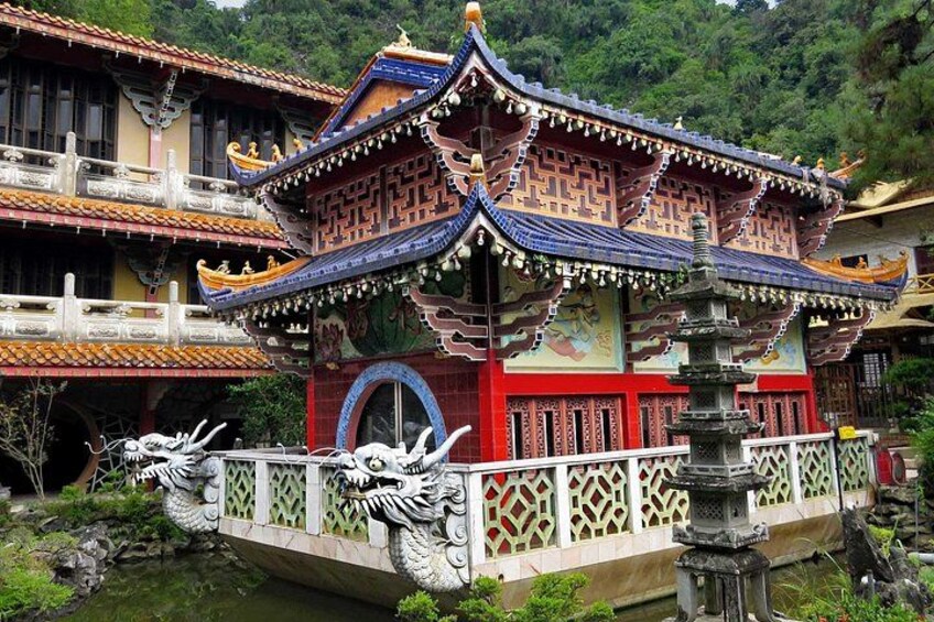 A traditional Chinese building with ornate architecture, a stone bridge, and a dragon statue. 1