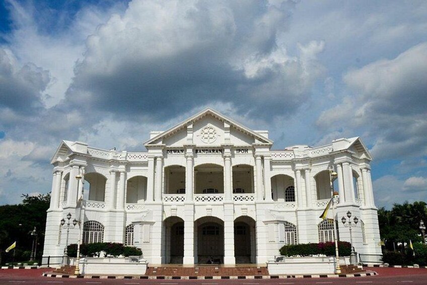 A large white colonial-style building with multiple arches and columns, a central entrance, and a flagpole. 4