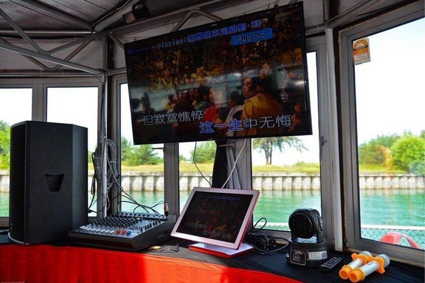 A control room with a large screen, a DJ mixer, a laptop, and audio equipment. 3