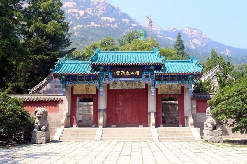 A traditional Chinese gate with a red door, blue roof, and stone lion statues on either side. 1