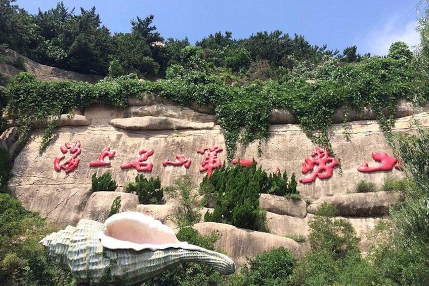 A rock face with carved Chinese characters and a large shell sculpture. 2