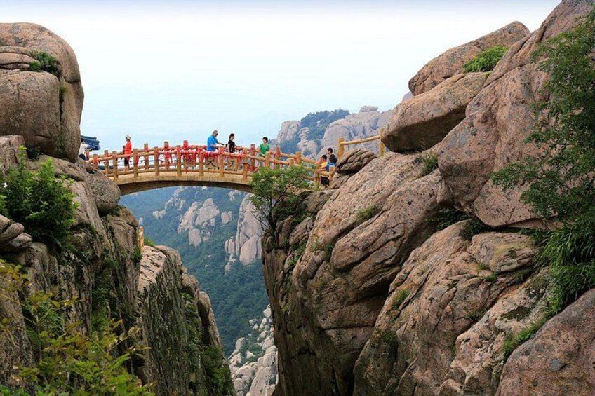 A wooden bridge over a cliff with people walking on it. 4